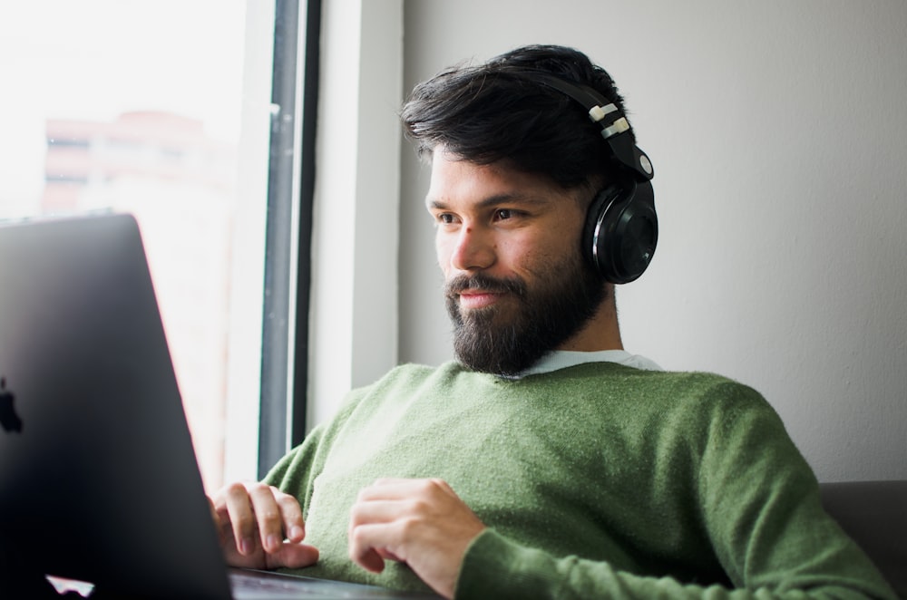 ヘッドフォンを着けてMacBookを見ている男性