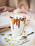 white mug with brown liquid topped with marshmallows