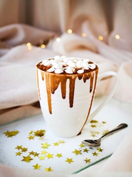 white mug with brown liquid topped with marshmallows