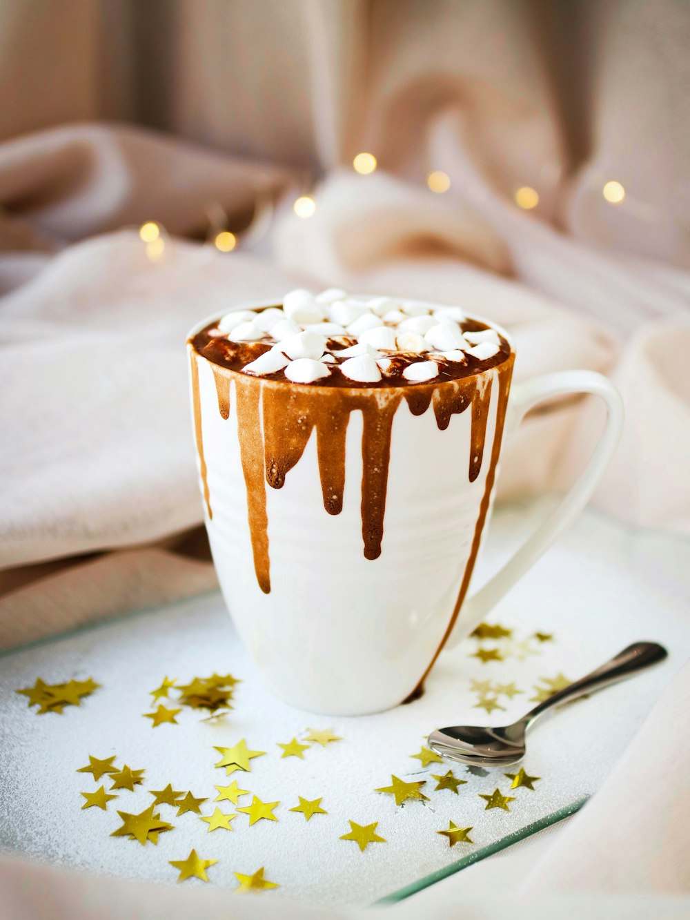 white mug with brown liquid topped with marshmallows