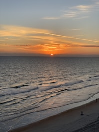 A serene beach scene with a beach chair and sunset.