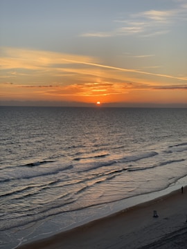 A serene beach scene with a beach chair and sunset.