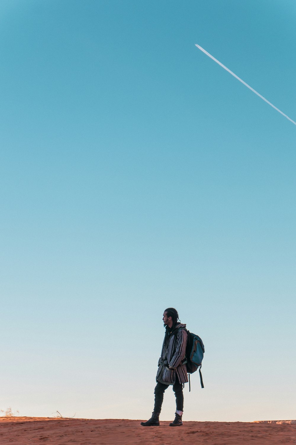 man wearing backpack standing on ground during daytime