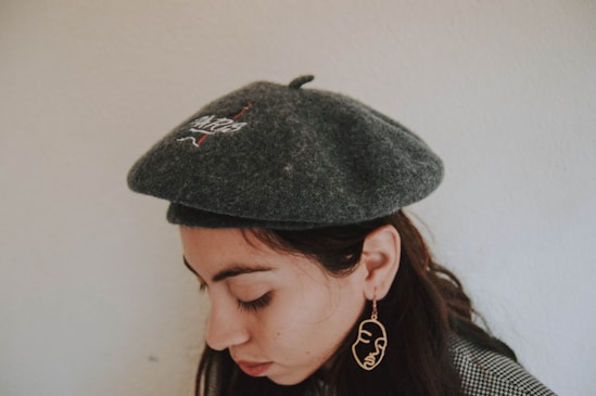 woman wearing gray hat standing beside wall
