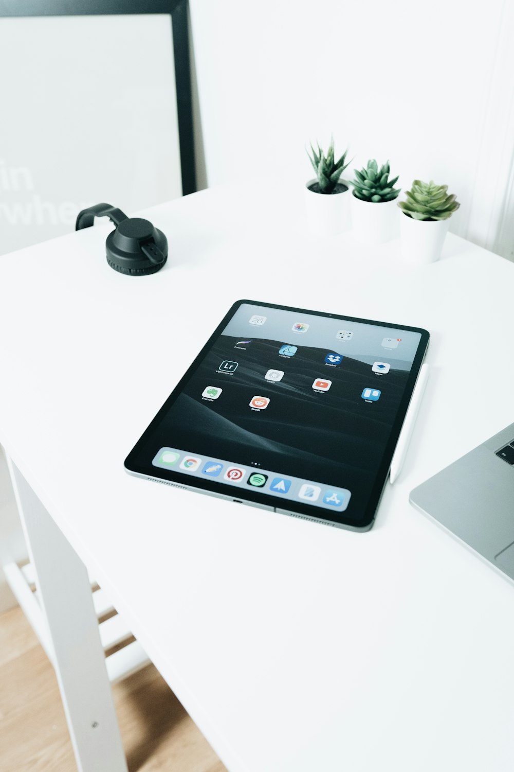 turned-on space gray iPad on white wooden table