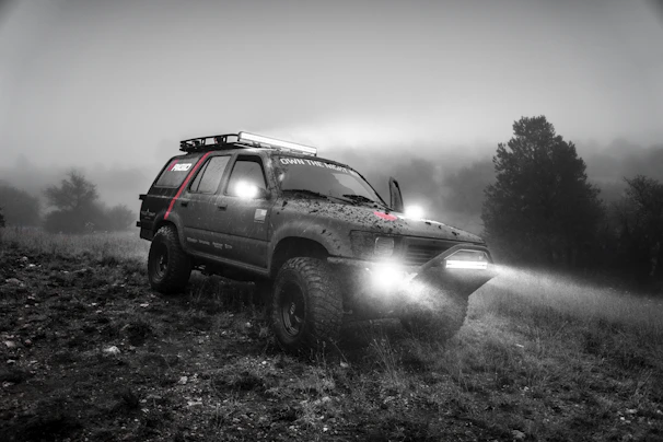 A rugged SUV outfitted with ultra-bright fog lights piercing through morning fog.