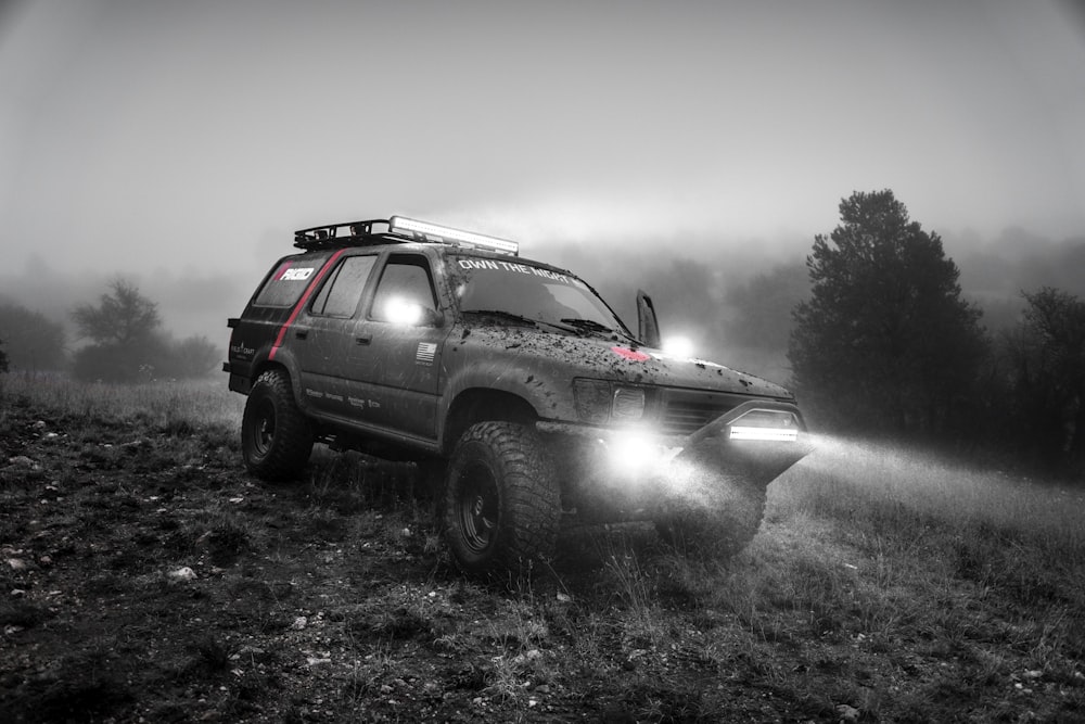 photographie en niveaux de gris d’un SUV près d’une forêt