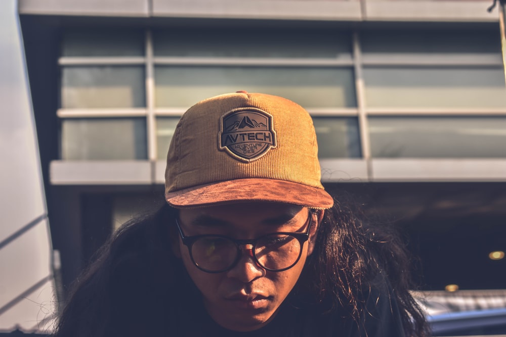 man wearing brown Avtech fitted cap and black shirt