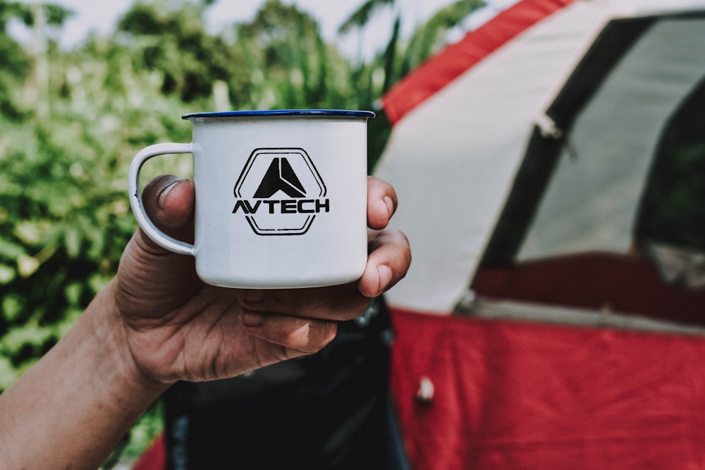 person holding white Avtech mug