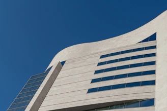 A sleek modern building with sharp lines and concrete gray facade under a clear sky.