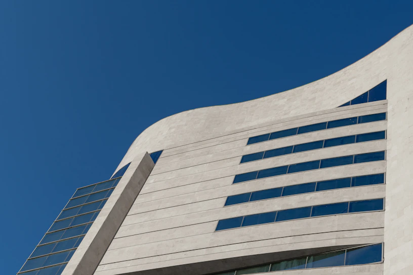 A sleek modern building with sharp lines and concrete gray facade under a clear sky.