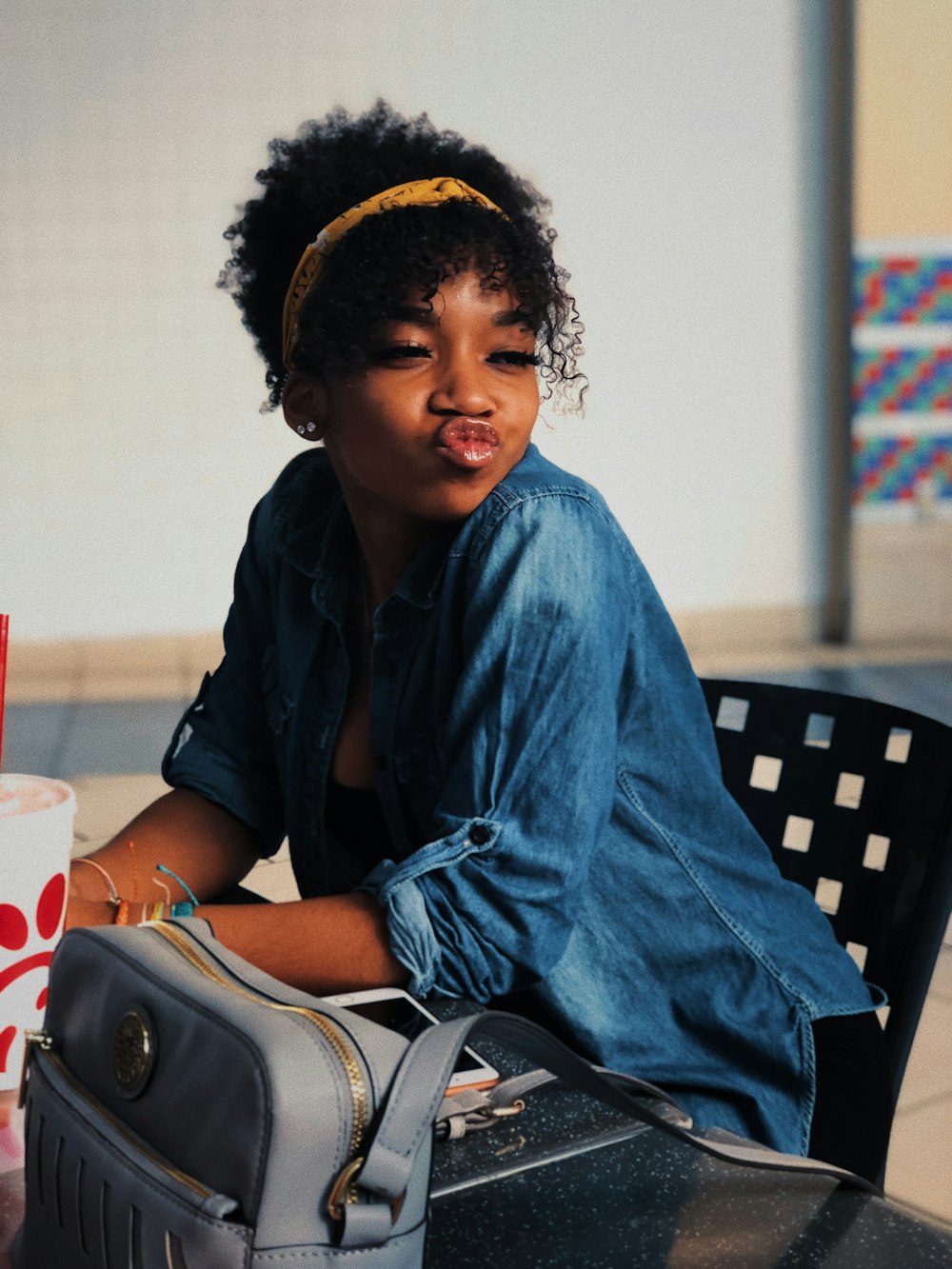 woman in blue denim shirt sitting chair pouting her lips