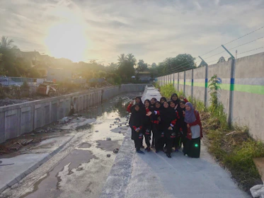 A group photo of volunteers smiling warmly during a foundation event at sunset.