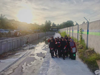 A group photo of volunteers smiling warmly during a foundation event at sunset.