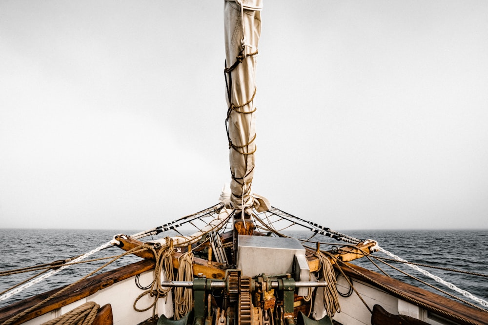 wooden yacht sailing at sea under grey sky