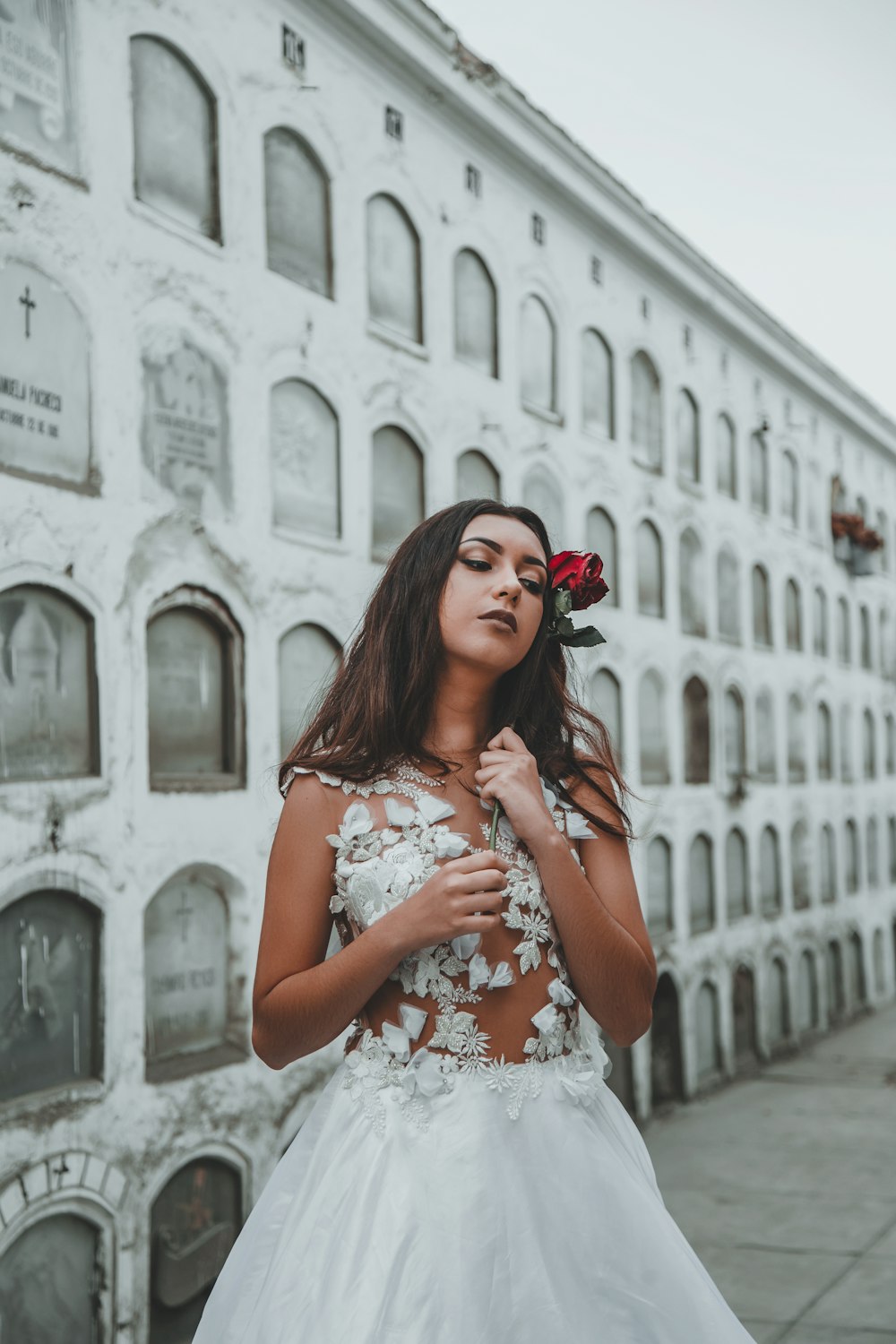 woman wearing wedding dress standing beside tombstone