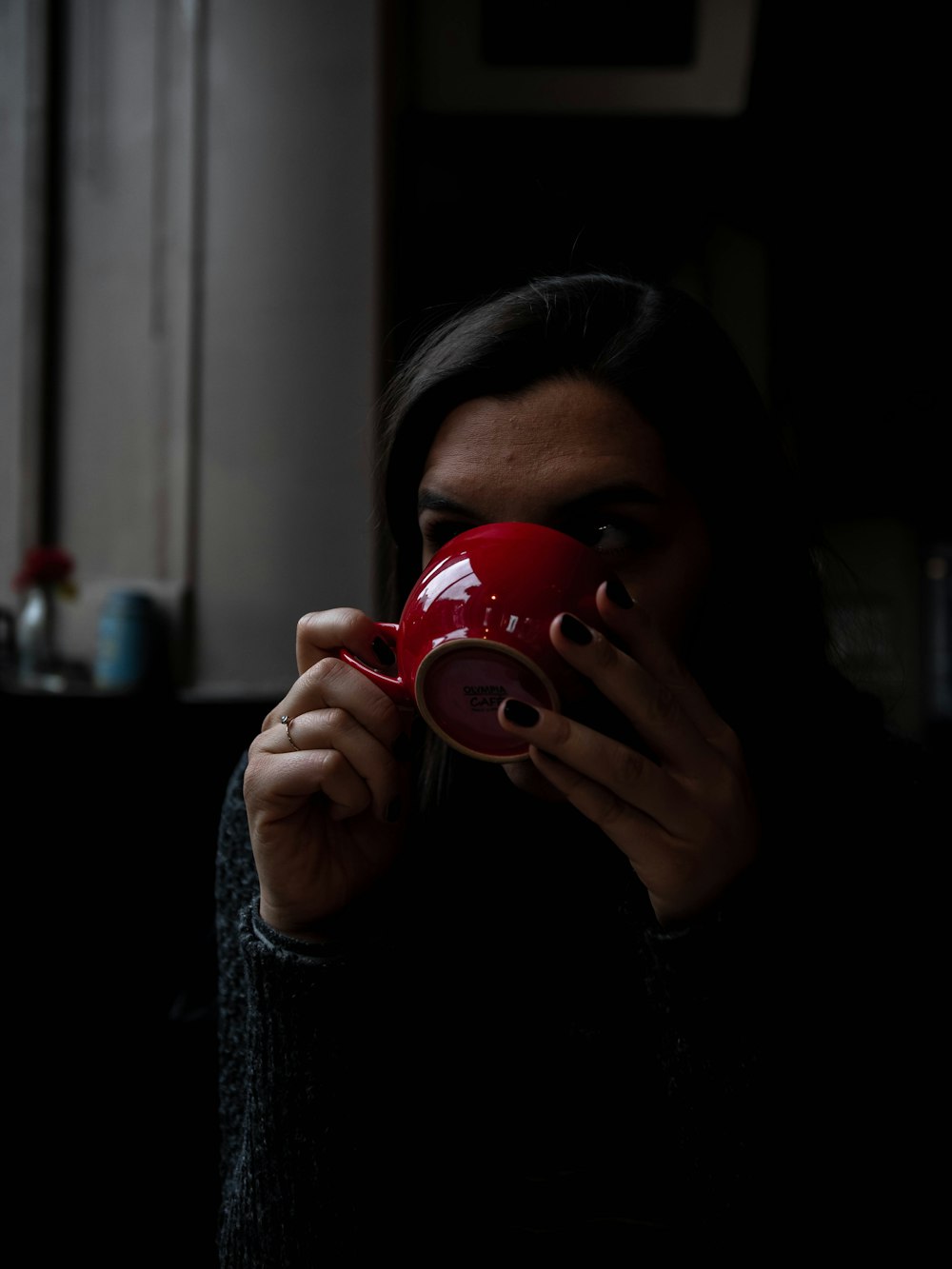 women drinking from red ceramic cup