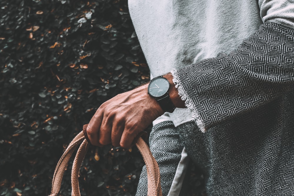 person wearing gray cardigan holding handbag