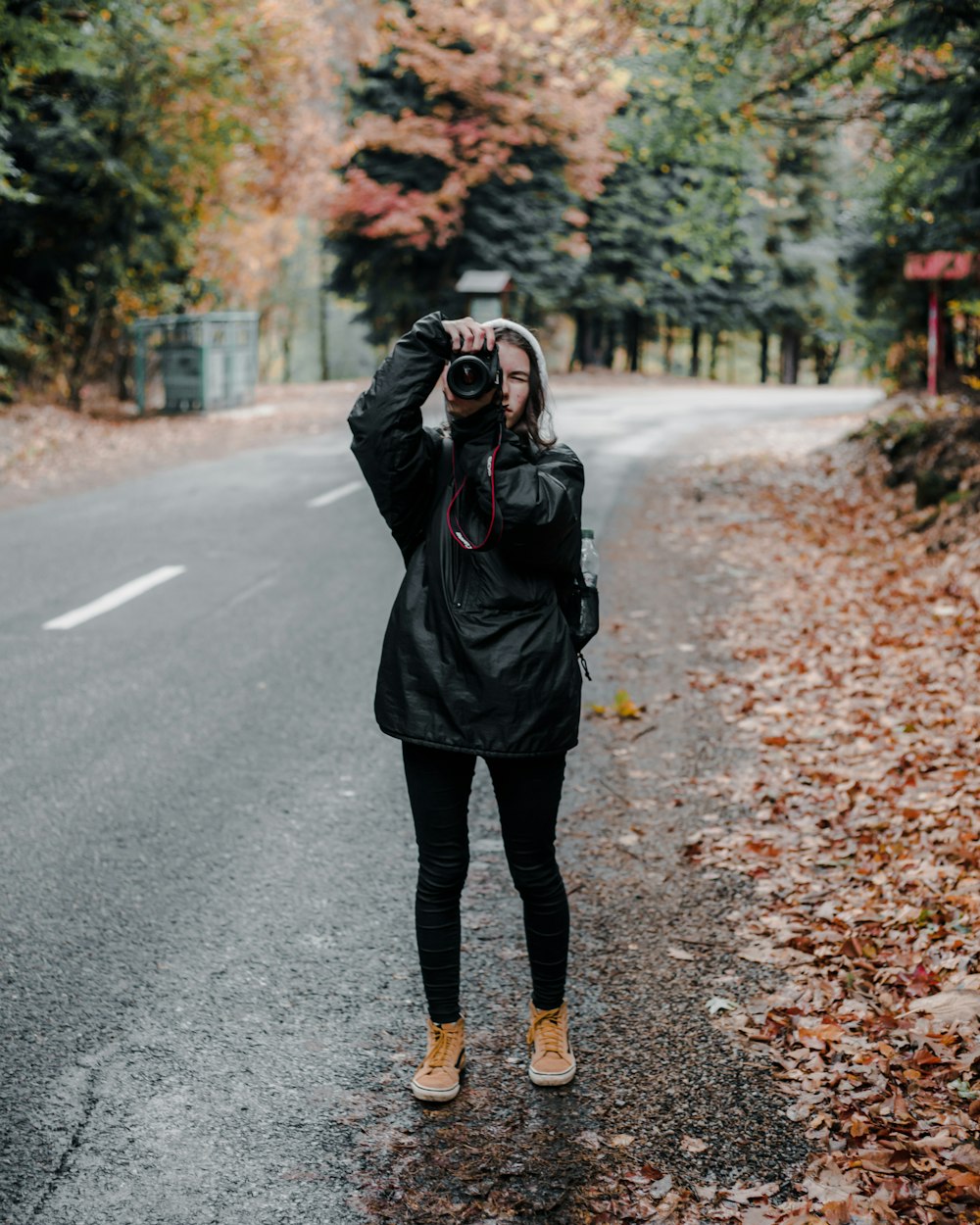 man holding camera standing on road