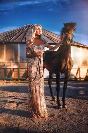 Elegant woman wearing Noble Gallop riding gloves beside a chestnut horse in a sunlit stable