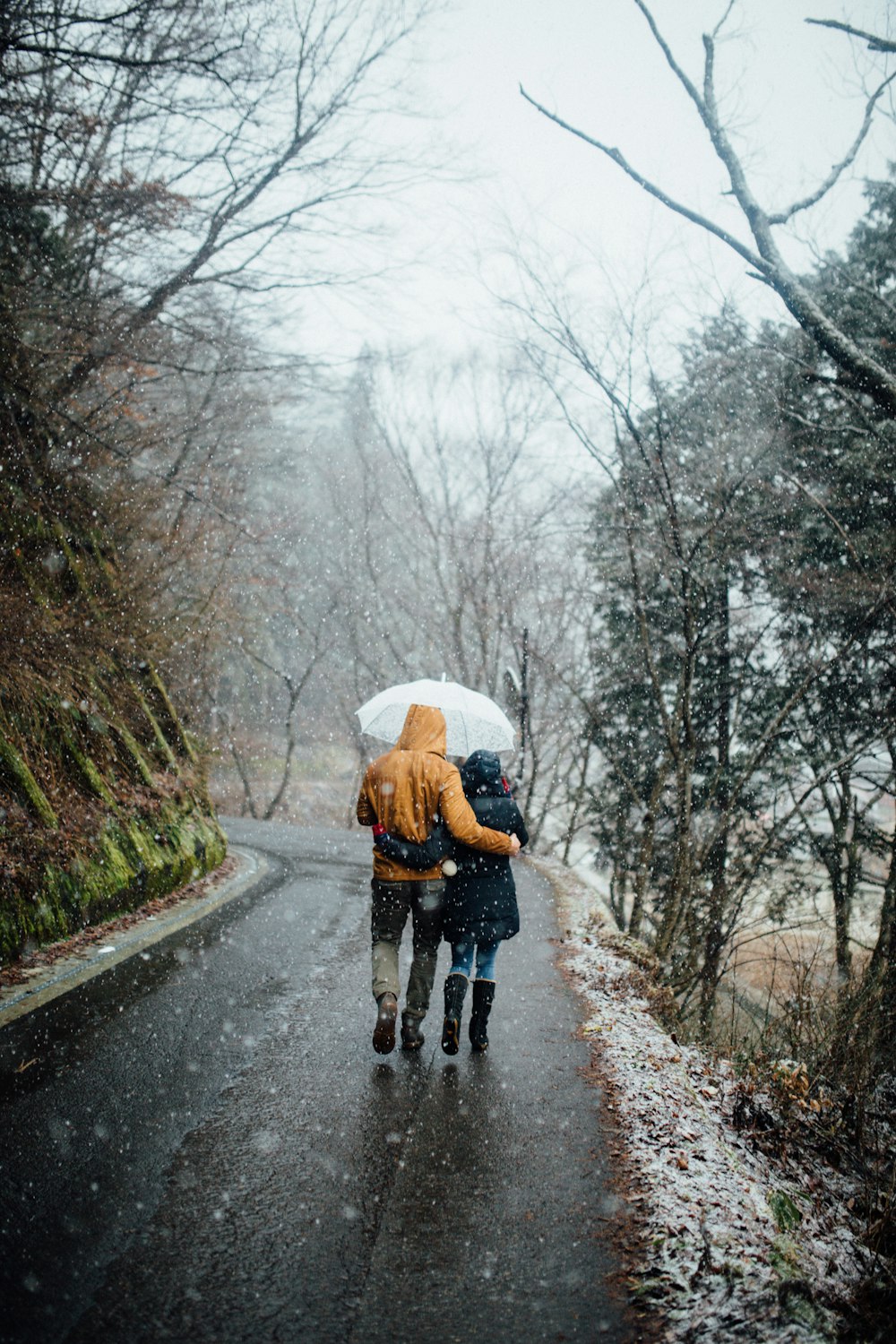 man and woman walking in the rain while holding umbrella