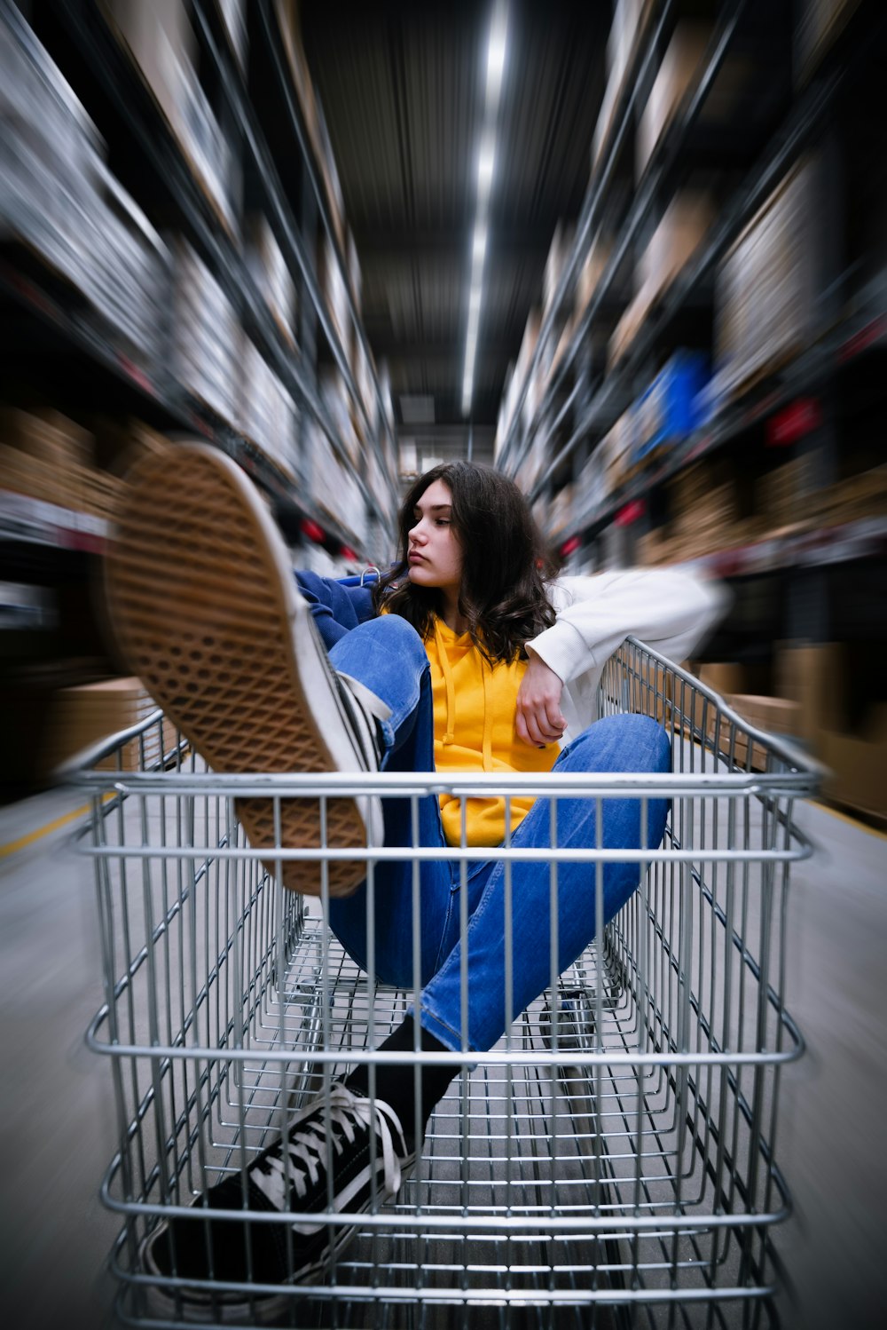 Selektive Fotografie einer Frau, die auf einem Einkaufswagen im Lager sitzt