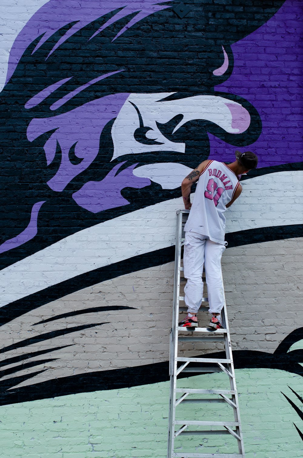 man standing on ladder and painting the wall
