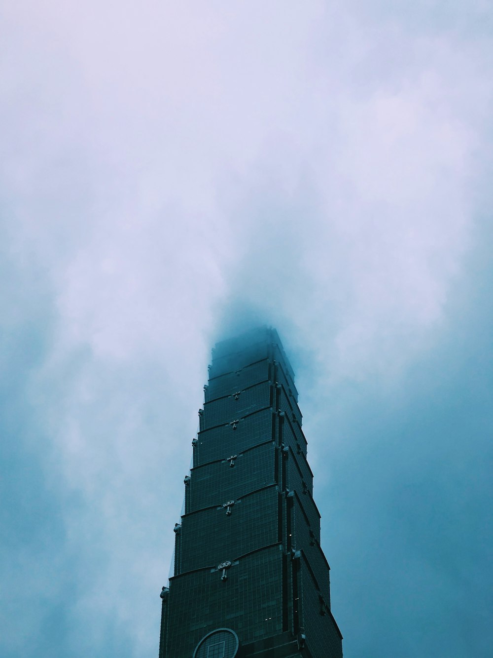 low angle photo of concrete building under blue sky and white clouds during daytime