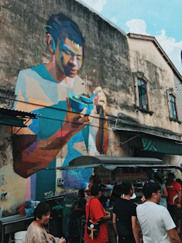 Street artists painting colorful murals as a crowd enjoys the festive atmosphere.