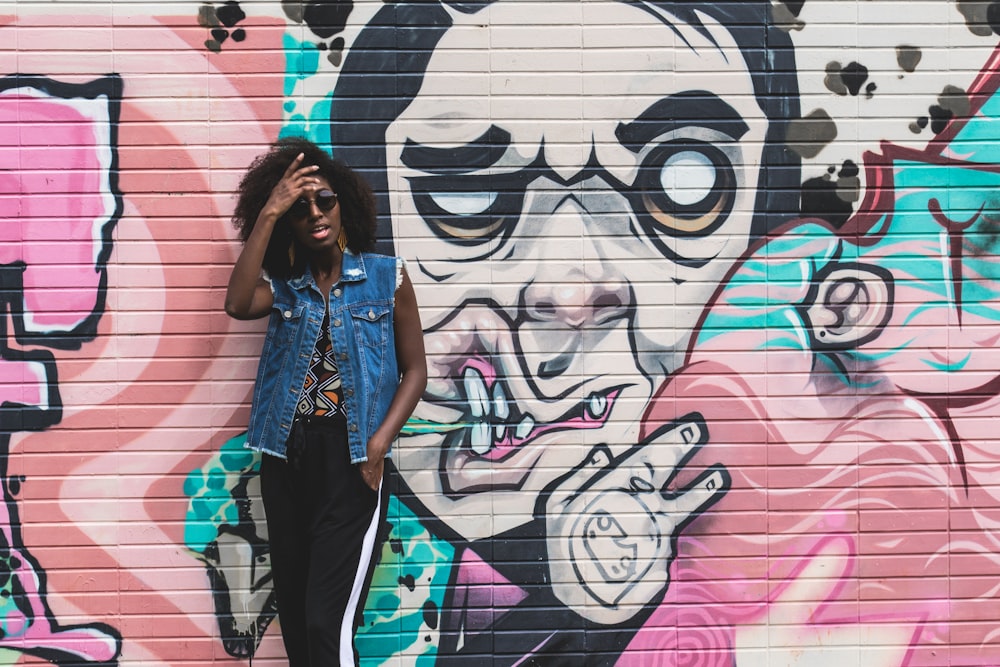 woman standing in front of wall with moral painting