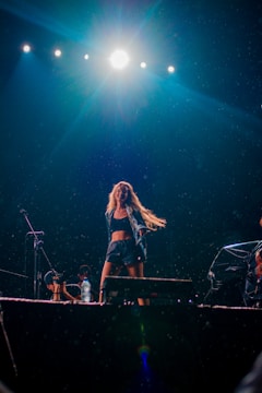 A dynamic performer dancing on stage with vibrant lighting.
