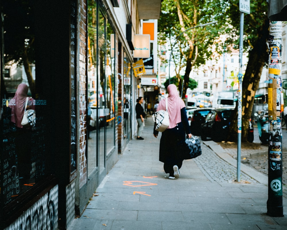 woman walking on street near street post during daytime