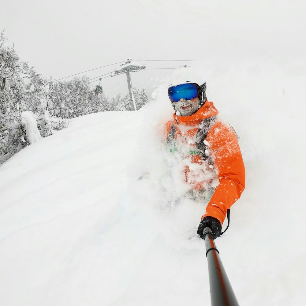 person wearing orange jacket on snow