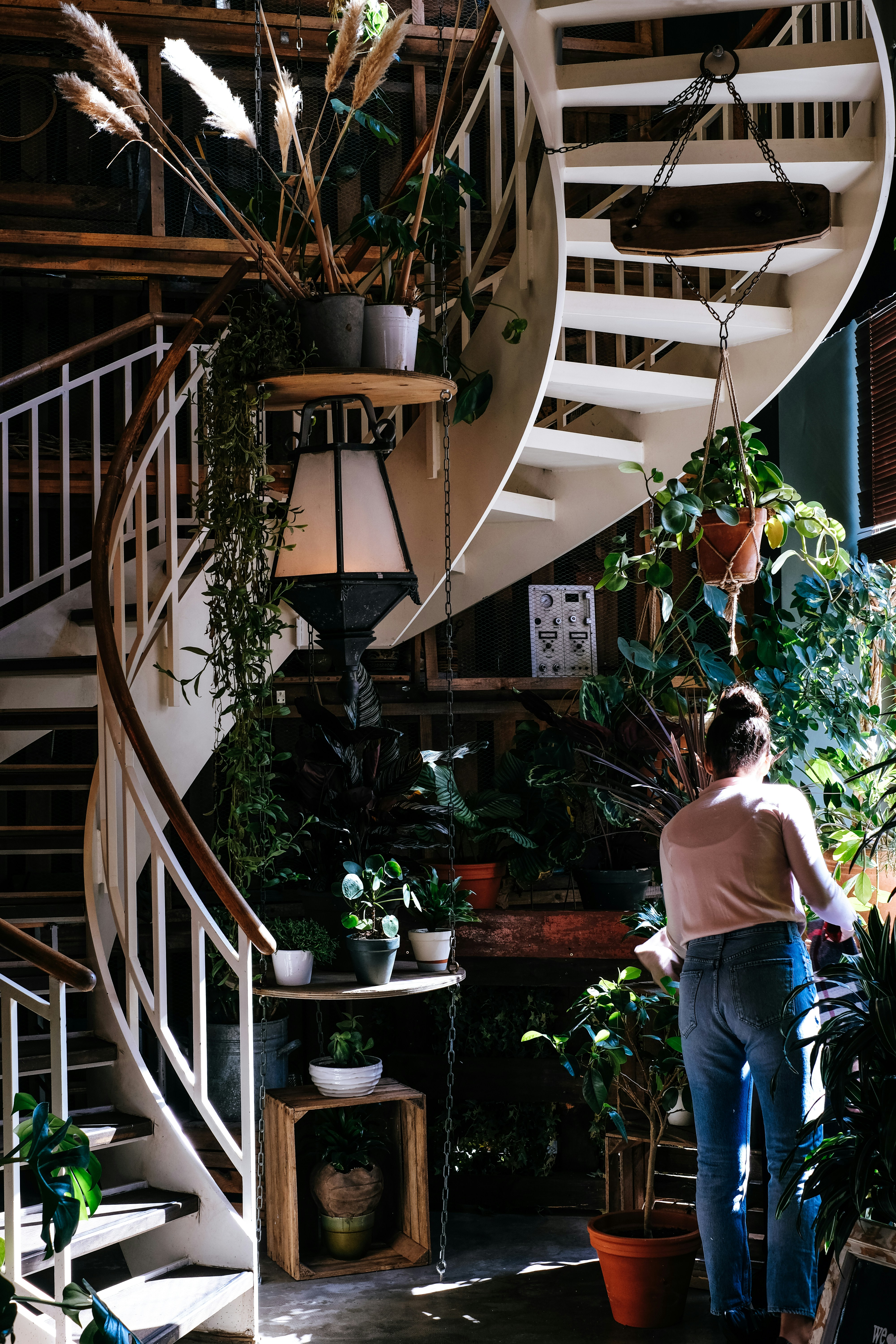 Woman stands next to a spiral staircase and organizes her apartment
