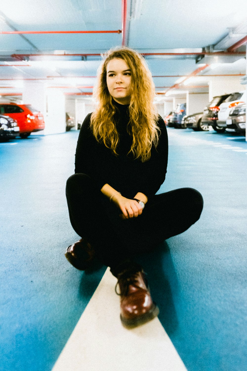 woman in black sweater and pants sitting on center of parking road