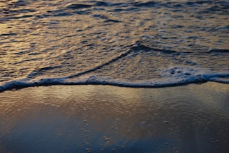 Golden sandy beach at sunset with gentle waves rolling in near the villa.