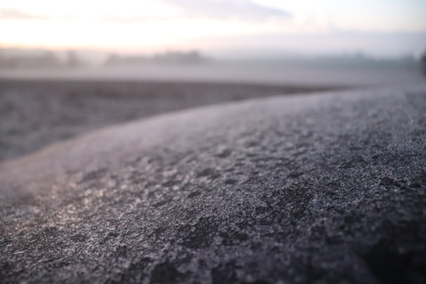A close-up of a cryogenic tank with frost on its surface, set against a rustic farm background.