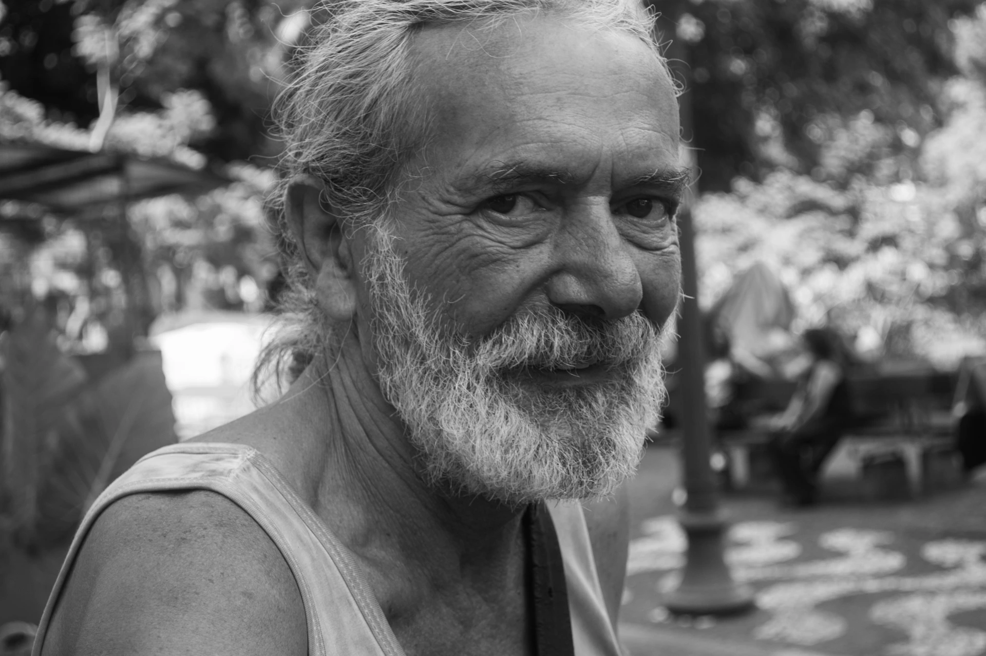 The old old man captured mid-laugh, completely at ease and free, with a gentle breeze ruffling the empty space around him.