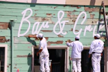 Close-up of painters carefully applying a fresh coat on a home's exterior siding.