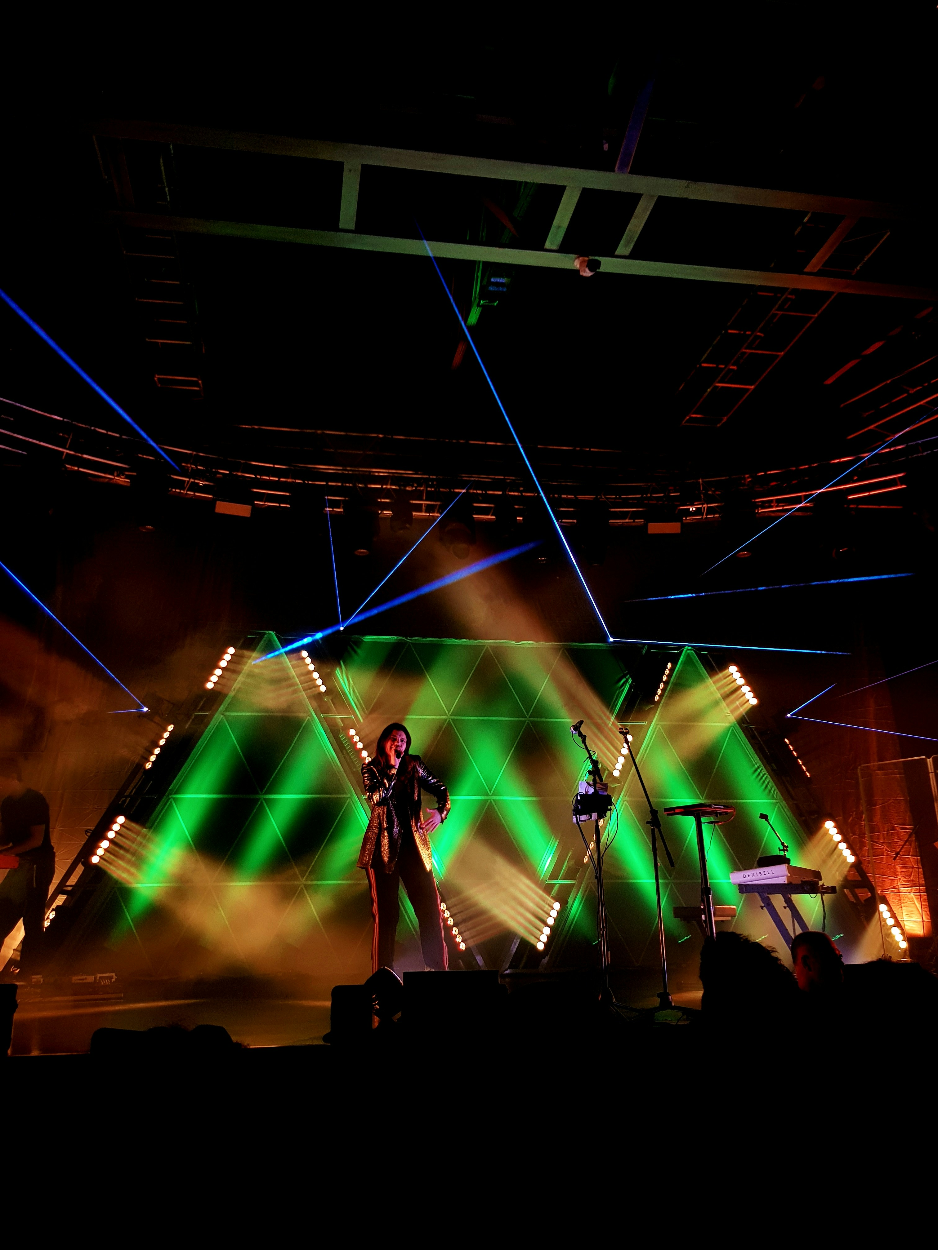 Massive e-sports arena stage with bright lasers, giant screens showing gameplay, and a cheering crowd in silhouette