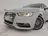 A car with seasonal tires parked in a snowy environment.