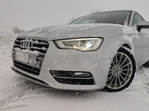 A car with seasonal tires parked in a snowy environment.