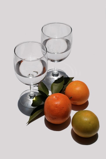 A set of modern glass tumblers with subtle patterns, displayed alongside fresh citrus fruits.