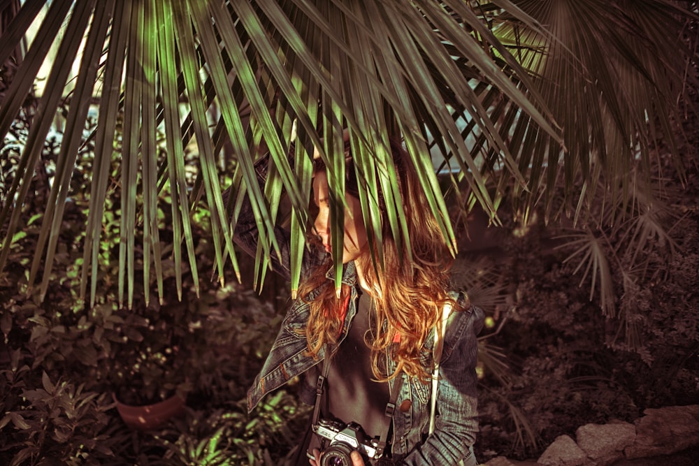 standing woman beside fan palm