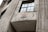 A concrete building features a decorative emblem on its facade, embossed with symbols and text. The structure showcases large vertical grooves and a window pane reflecting the overcast sky. The architecture hints at an industrial or governmental style.