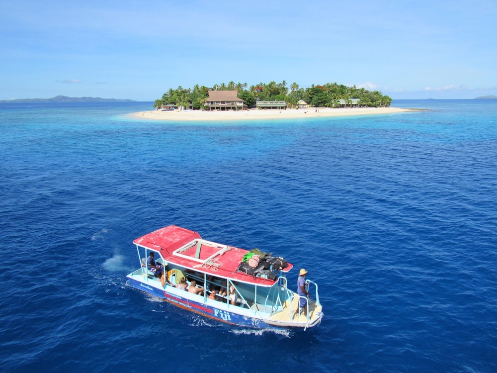people riding boat on body of water near island during daytime