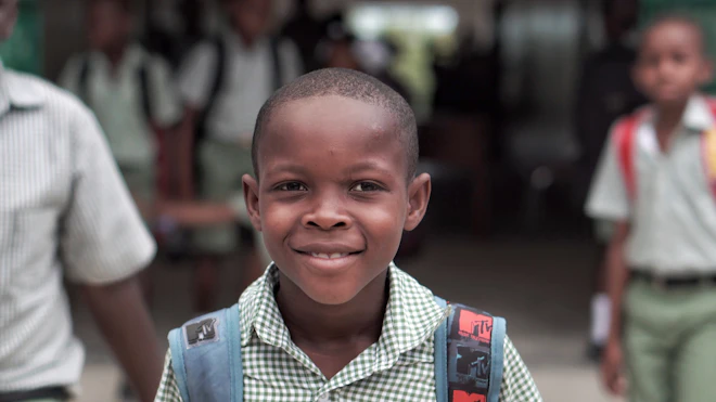 Niño sonriente con su morral listo para entrar al colegio