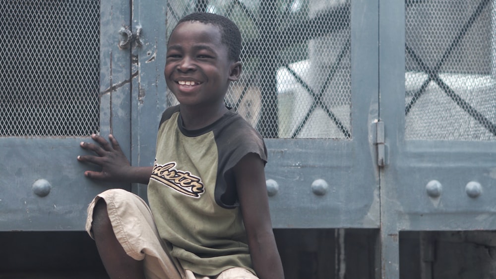 smiling boy sitting beside gray metal board