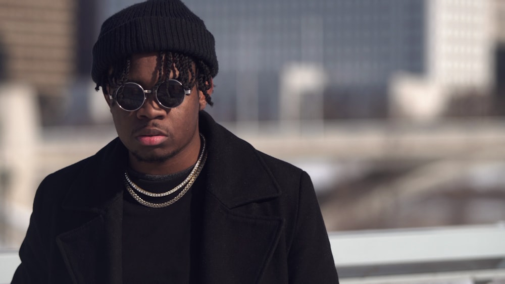 Fotografía de enfoque selectivo del hombre vestido con gorro de punto negro y gafas de sol