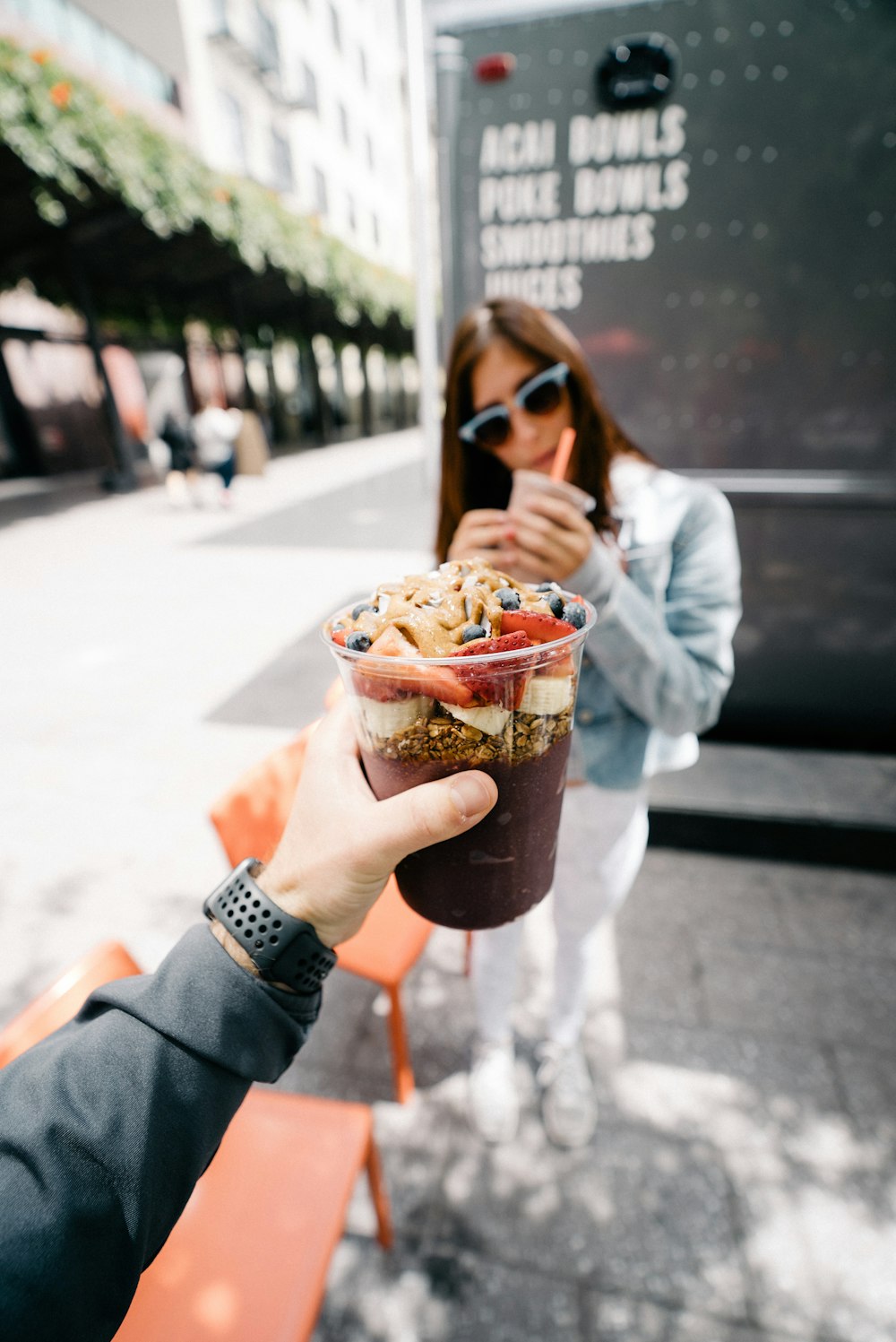 man in grey shirt holding a cup of dessert